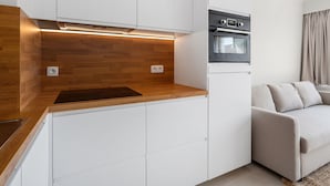 Eine moderne Küche mit weißen Schränken, einer Holzauskładung und einem eingebauten Backofen.