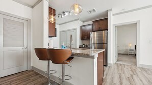 A modern kitchen with a central island, stainless steel appliances, and pendant lighting.