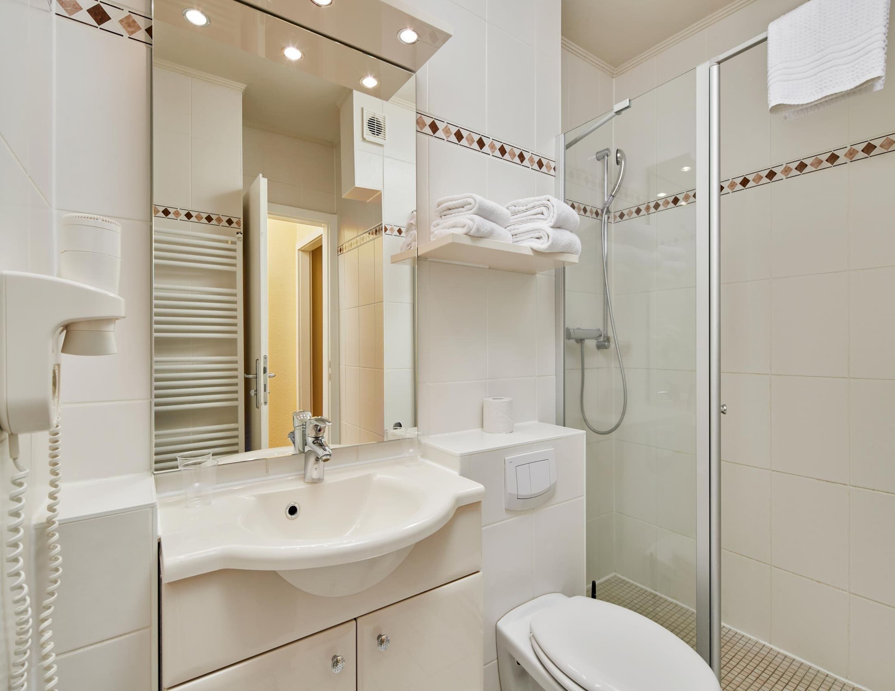 Een moderne badkamer met een wastafel, spiegel en toilet.