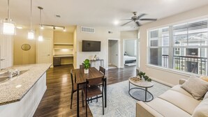 A modern kitchen with a dining area, a living room with a sofa, and a balcony with a view. - Cullen 4307 I Parking I Pool I Gym I 2Bd/2Bth (Houston)