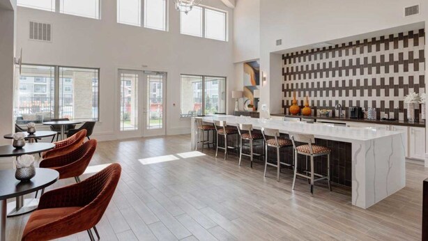 A spacious kitchen with a large island, modern bar stools, and a decorative wall.
