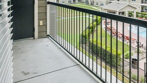A balcony with a view of a swimming pool and apartment buildings.