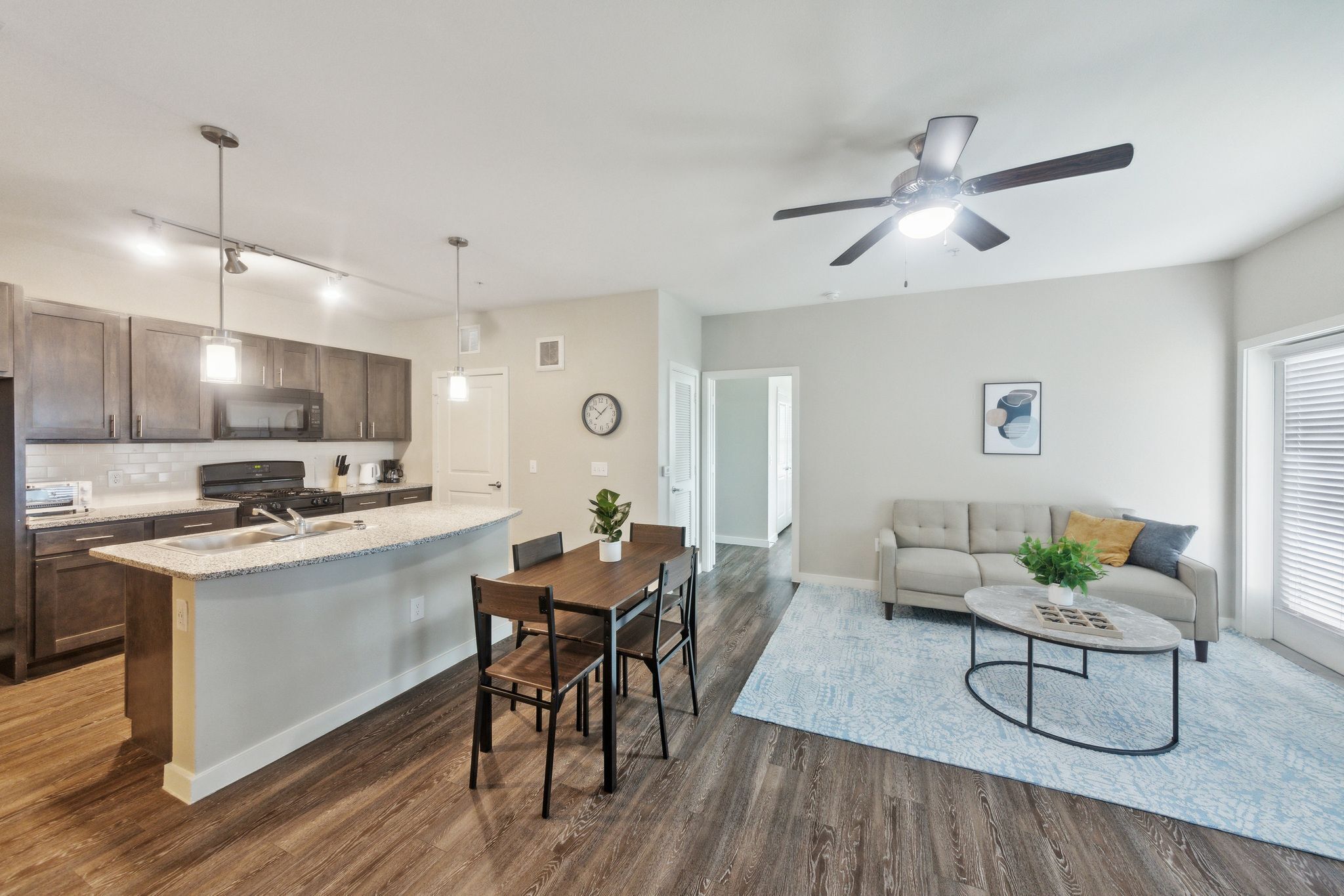 A modern kitchen with a central island, dining area, and a living room with a sofa and coffee table.
