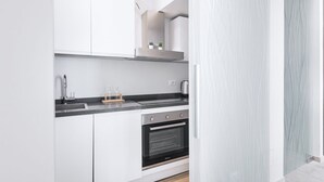 Una cocina moderna con armarios blancos, horno de acero inoxidable y encimera negra.