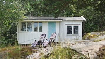 A small cabin with a porch, two chairs, and a blue door.