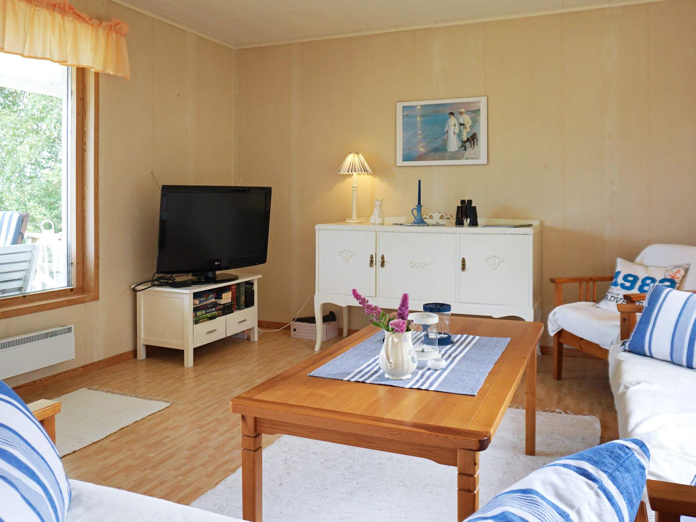 A furnished living room with a television, a cabinet, a sofa, and a table with a placemat.