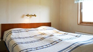Una camera da letto con un letto, una lampada a parete e una finestra con tenda.