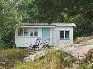 A small cabin with a porch, two chairs, and a window. - 6 Person Holiday Home in Kungshamn (Kungshamn)