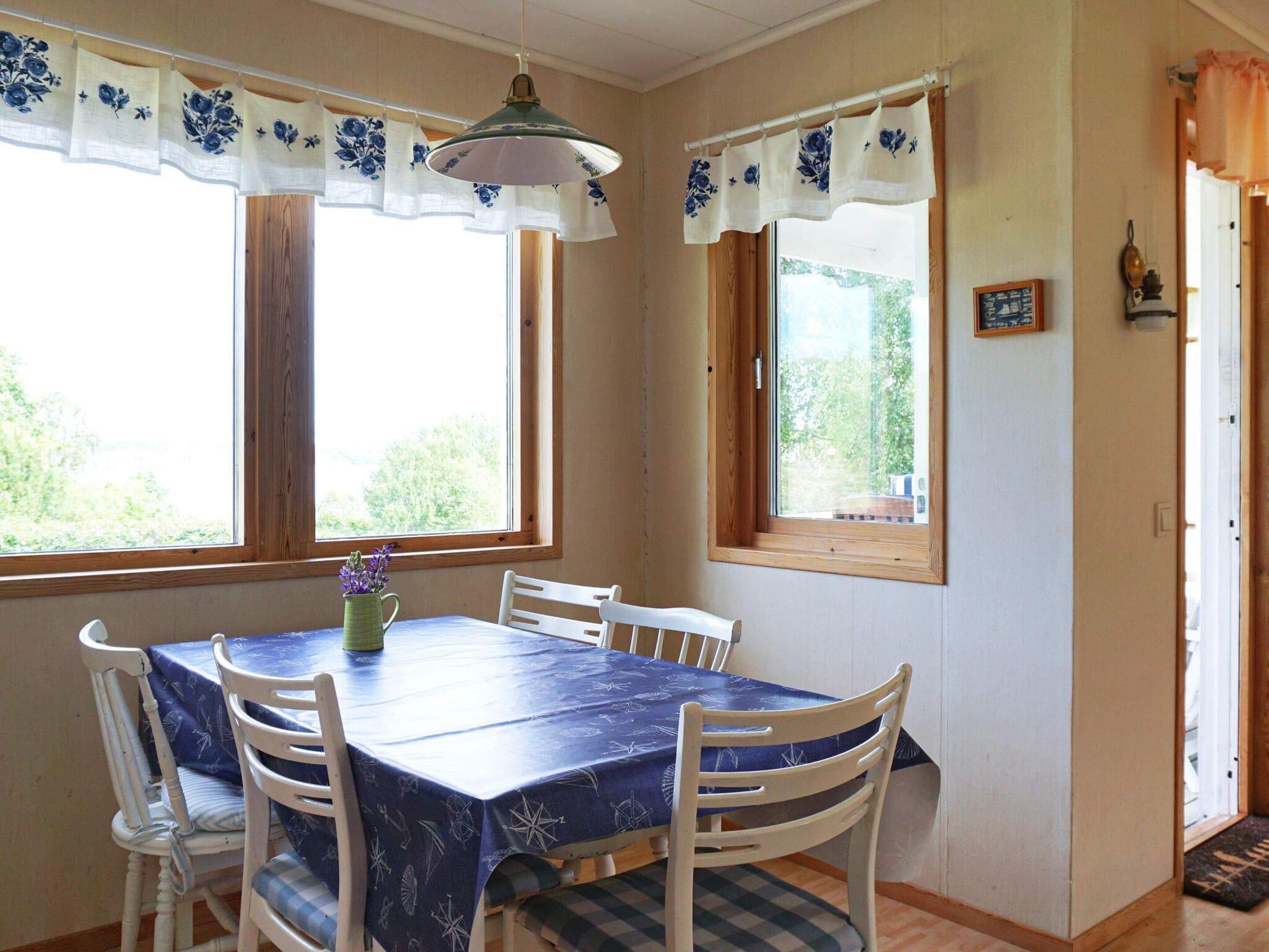A dining area with a table and chairs, a window with curtains, and a door.
