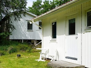 A white wooden house with a porch and a small table and chair. - 6 Person Holiday Home in Kungshamn (Kungshamn)