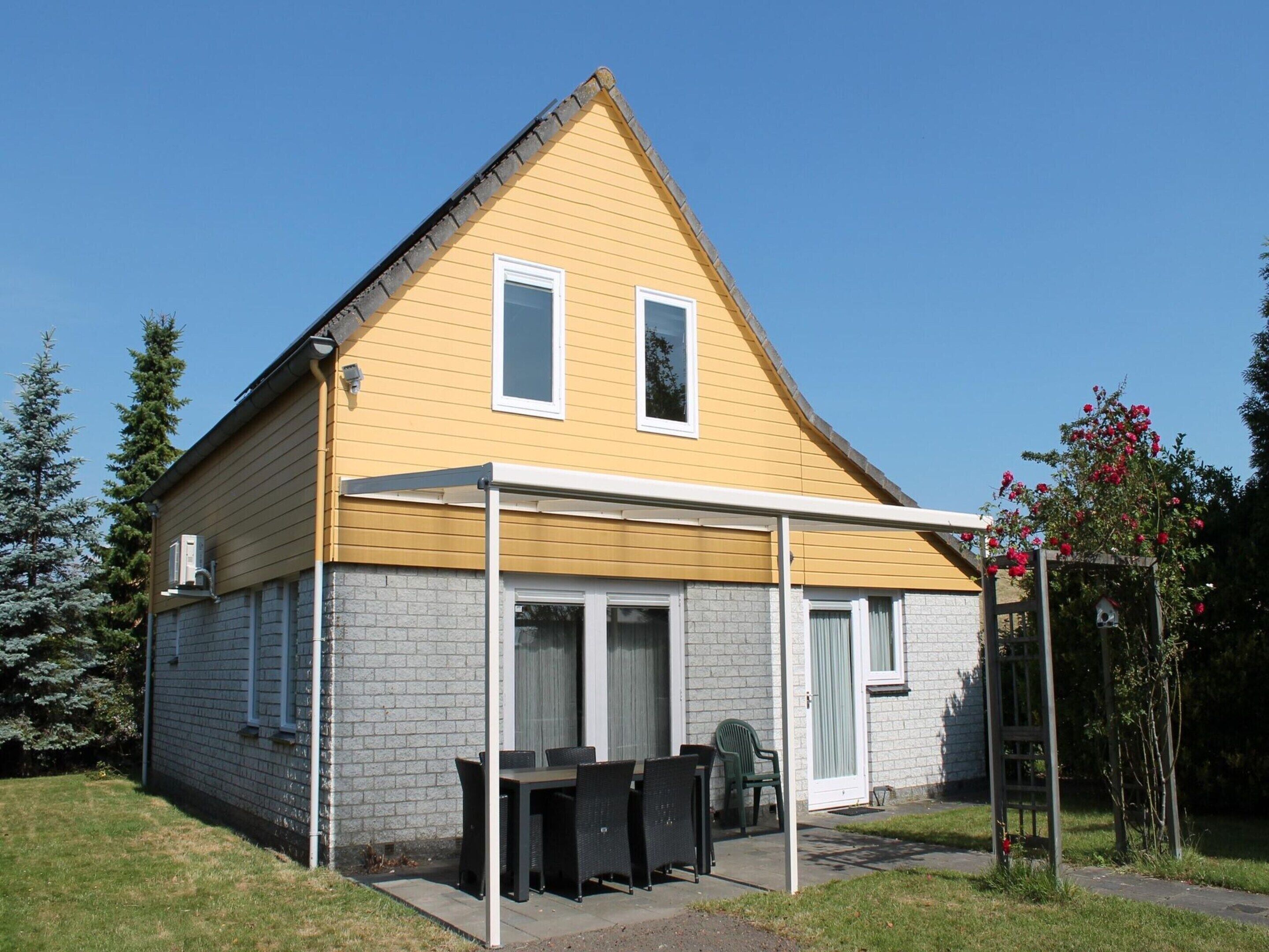 A two-story house with a yellow exterior and a covered patio area.