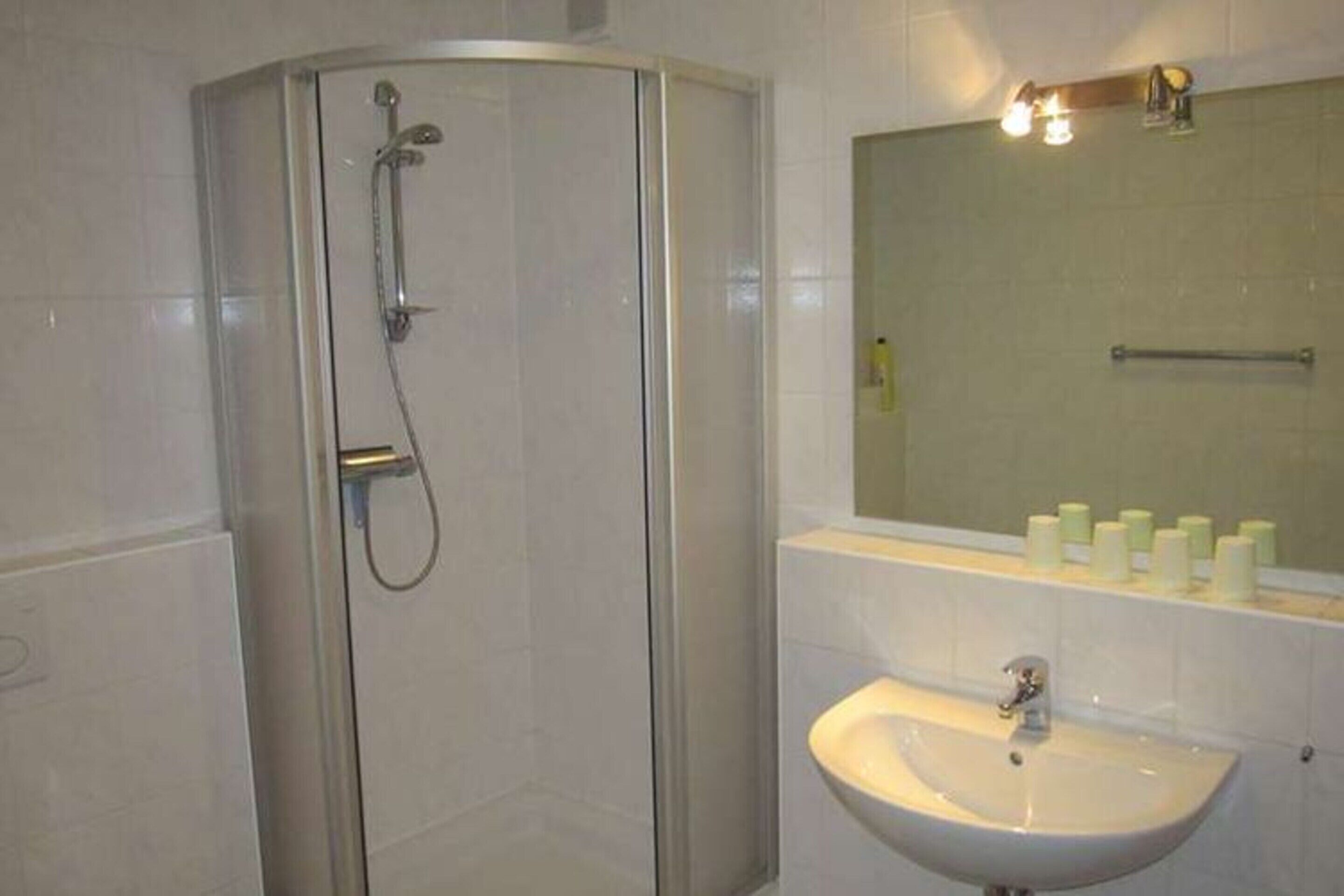A bathroom with a glass-enclosed shower, a sink, and a mirror above it.