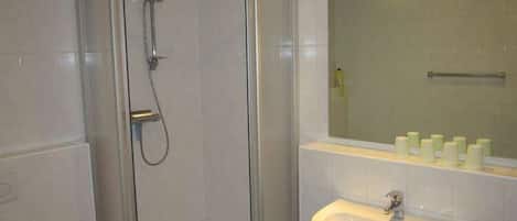 A bathroom with a glass-enclosed shower, a sink, and a mirror above it.