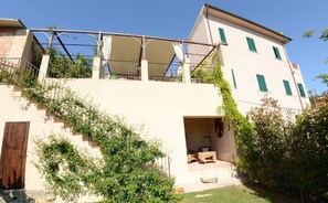 Un immeuble à plusieurs étages, avec un escalier menant à un espace extérieur aménagé, couvert et destiné à accueillir des clients.