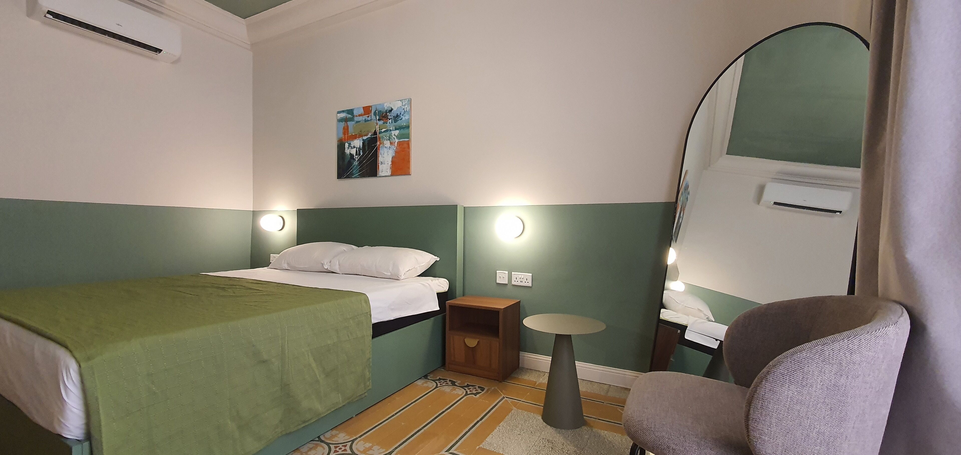 Une pièce comprenant un lit, une table de chevet, une chaise et un tableau accroché au mur.