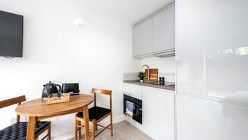 A modern kitchen with white cabinets, a wooden dining table, and a black oven.