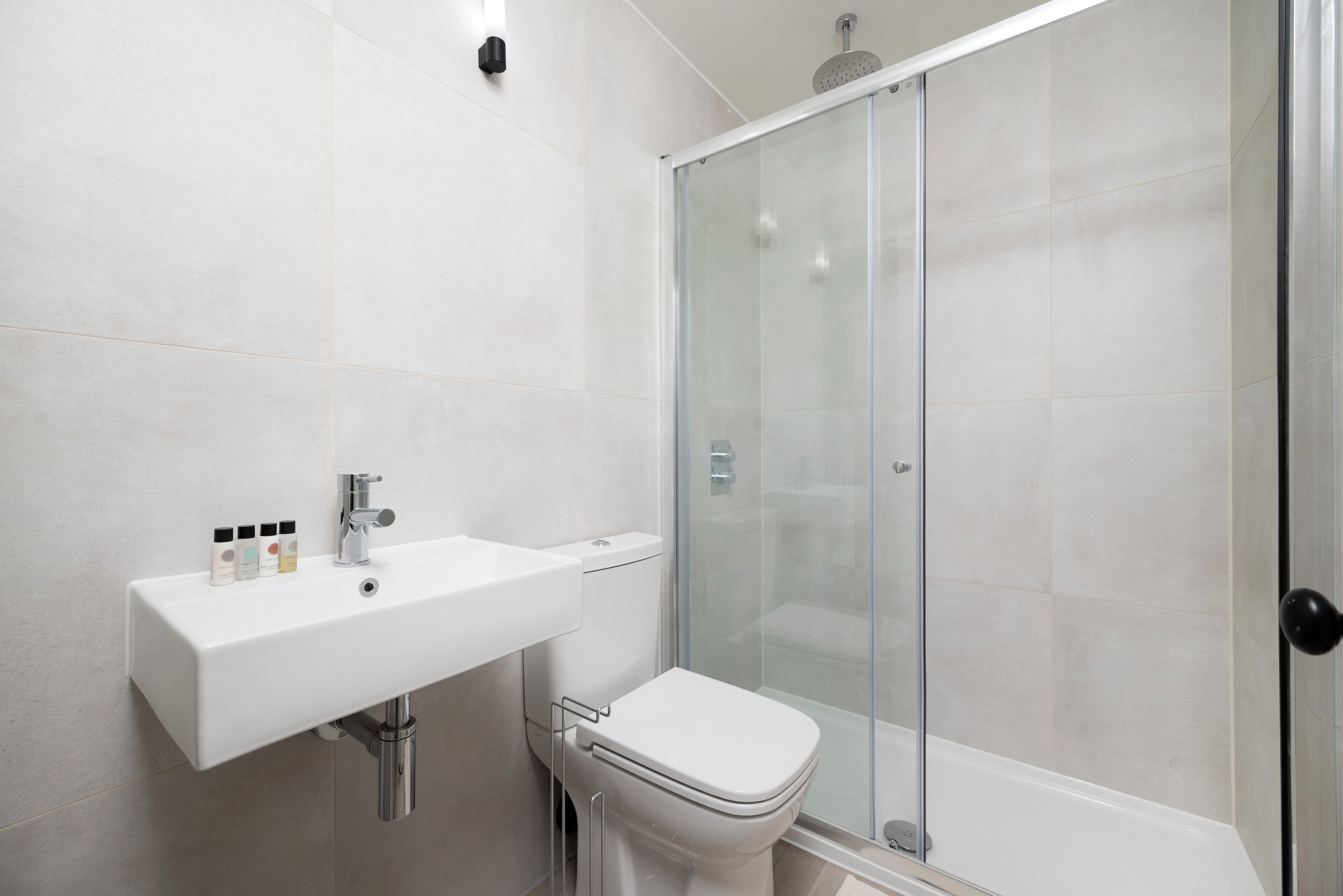 Ein modernes Badezimmer mit Waschbecken, Toilette und Duschkabine aus Glas.