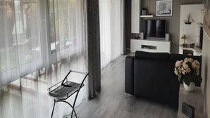 A modern living room with a sofa, a TV, and a ceiling fan. - Ferienhaus im Skandinavischen Stil (Mirow)