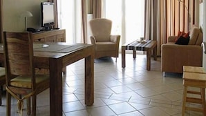 Un soggiorno con un tavolo da pranzo in legno, una poltrona beige, un divano e un tavolino da caffè.