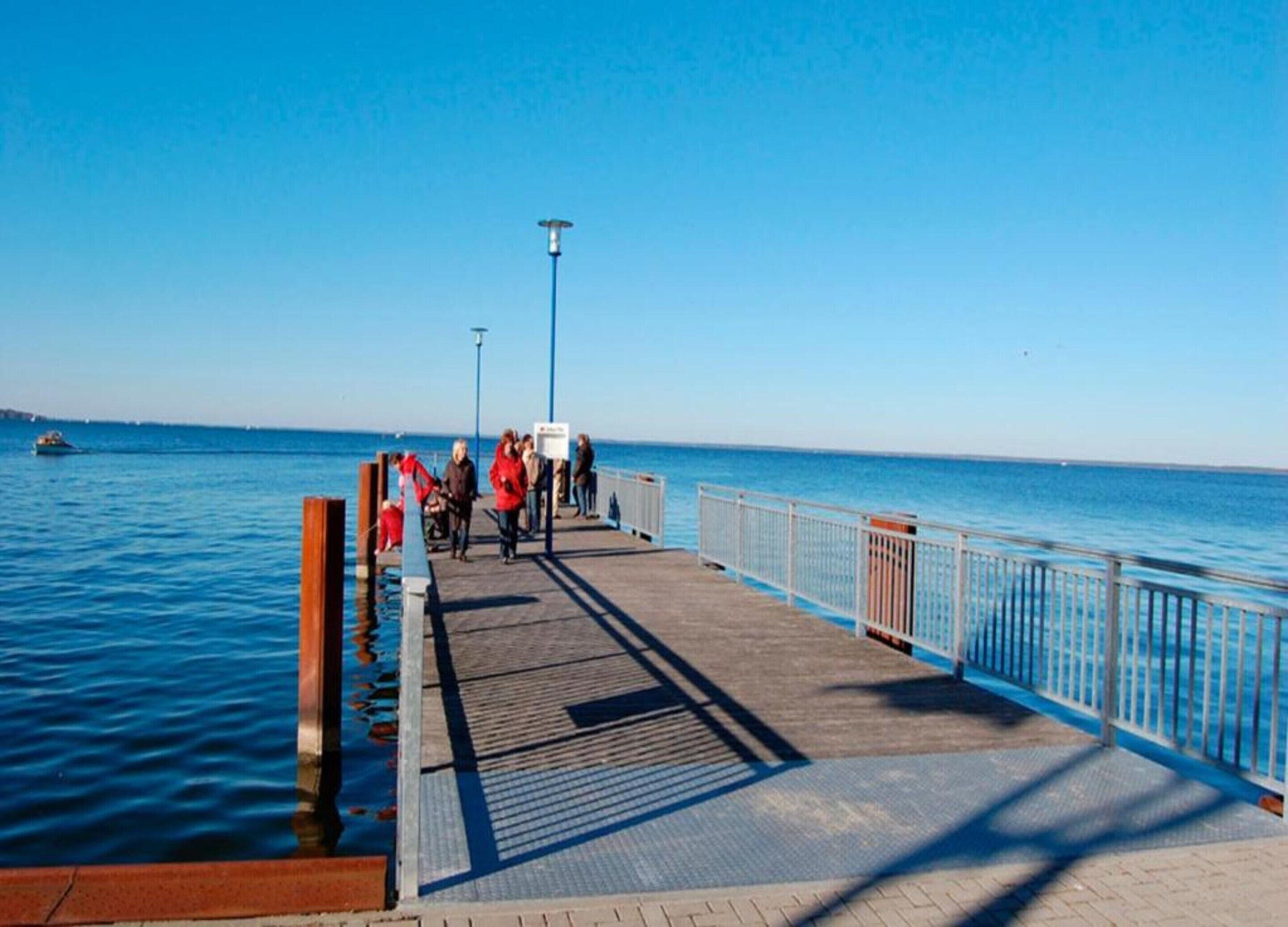 A pier extending into calm blue waters with a clear sky.