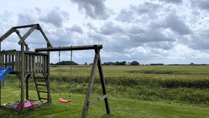 Un columpio de madera en un campo cubierto de césped bajo un cielo nublado.