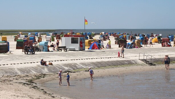 Una playa con numerosas cabañas de playa coloridas y una estación de salvavidas.