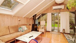A cozy living room with a wooden ceiling, a sofa, a coffee table, and a large window. - Cozy Retreat in Stenstrup - By Traum Ferienwohnungen (Hojby)