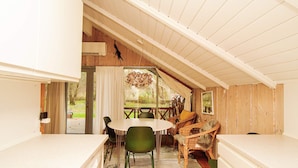 A cozy kitchen with a dining area, wooden walls, and a view of the outdoors. - Cozy Retreat in Stenstrup - By Traum Ferienwohnungen (Hojby)