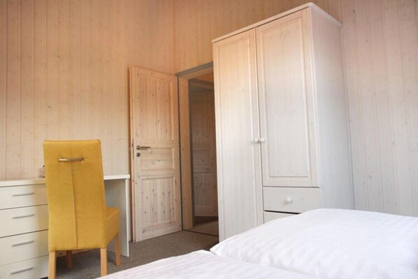 A bedroom with a bed, a wardrobe, a desk, and a chair. - Exklusives Skandinavisches Ferienhaus (Mirow)