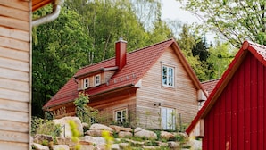 A wooden house with a red roof, surrounded by rocks and trees. - Ferienhaus in Schierke mit Garten (Wernigerode)