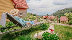 A person relaxing on a sun lounger in a grassy area with a house in the background. - Ferienhaus in Schierke mit Garten (Wernigerode)