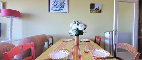 A dining room with a striped tablecloth, a vase of flowers, and two framed artworks on the wall.