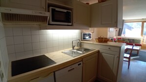 A compact kitchen with white cabinets, a microwave, a sink, and a dishwasher.