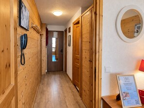 A hallway with wooden walls, a telephone, a mirror, and a sign for SAPO massages. - Renovated apt, ski-in/ski-out with bright balcony (Méribel)