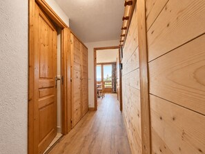 A wooden hallway with a door on the left and a window on the right. - Renovated apt, ski-in/ski-out with bright balcony (Méribel)