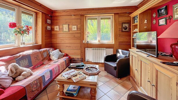Un accogliente soggiorno con arredamento in legno, un divano, un tavolino da caffè con dei libri, un televisore e una parete rossa con quadri.