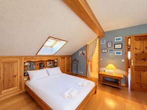 Una camera da letto con soffitto spiovente, struttura del letto in legno, una finestra a lucernario e un comodino con lampada.