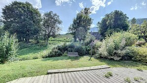 Un terrazzo in legno con una panchina e un muro in pietra in un rigoglioso giardino.