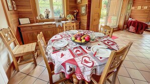 Una sala da pranzo in legno con un tavolo rotondo apparecchiato per quattro persone, circondato da sedie di legno.