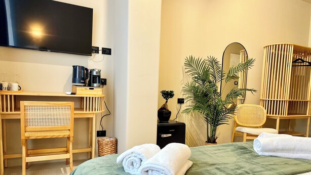 Une chambre d’hôtel comprenant un lit, un bureau avec un ordinateur, une chaise, une télévision et un miroir.