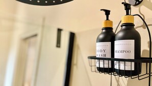 Une étagère en métal noir sur laquelle sont posées deux bouteilles de gel douche et de shampoing.