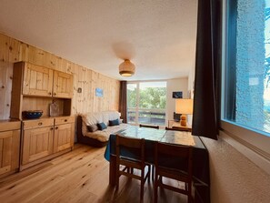 Una habitación acogedora con armarios de madera, una cama, una mesa de comedor con sillas y un ventanal grande.