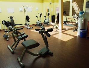 Un gimnasio con diferentes máquinas de ejercicio, incluyendo cintas de correr, bicicletas estáticas y aparatos de pesas.