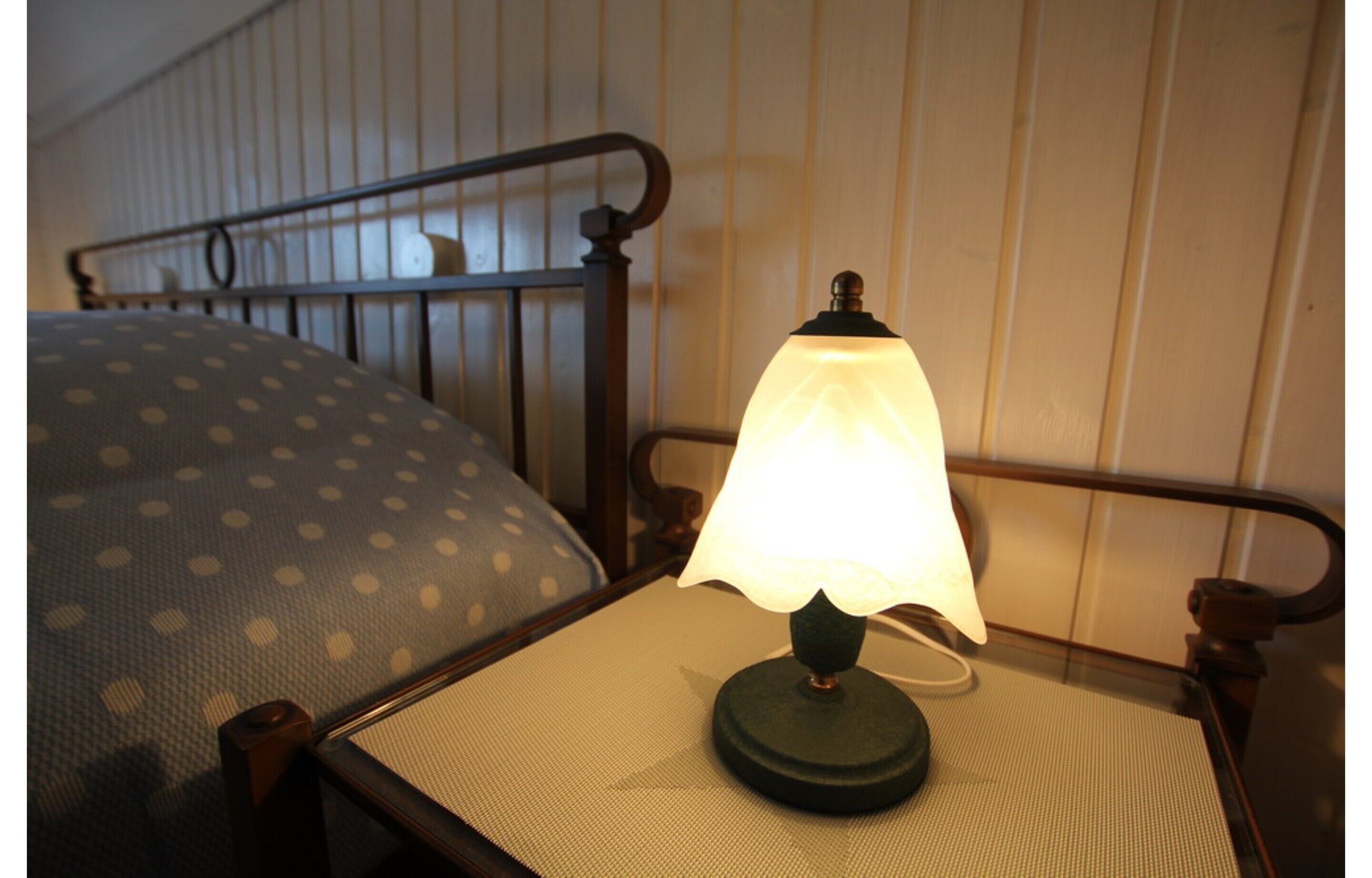 A bed with a polka dot pillow and a bedside table with a lamp.