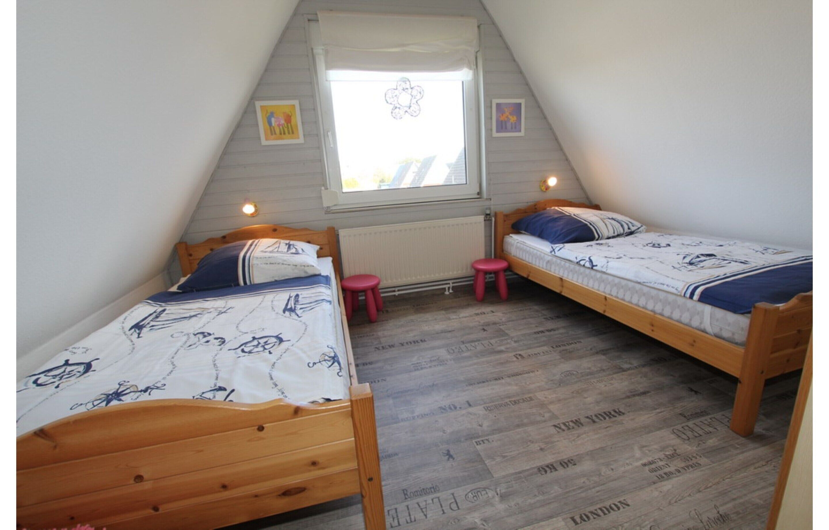Ein kleines, dreieckiges Schlafzimmer im Dachgeschoss mit zwei Holzbetten, einem Fenster mit Aussicht und einer Heizung.