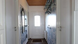 A hallway with wooden flooring, white walls, and a ceiling light. - Ferienhaus Toms Hutte mit Terrasse in Dornum (Dornum)