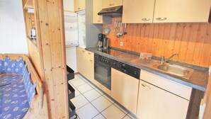 Une cuisine compacte avec des meubles en bois, un four encastré, un lave-vaisselle et un évier.