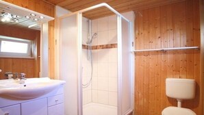 Une salle de bain avec douche, toilettes et lavabo.