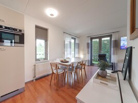 Una cocina moderna con horno empotrado y comedor con mesa y sillas blancas.