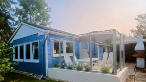 Ein blaues Haus mit Wintergarten und Schornstein.